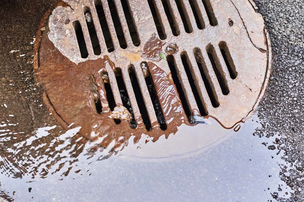 water draining into a sewer manhole