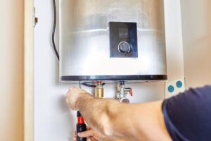 the man tightens the pipe nut in the water heating system. the master installs the water heater. the concept of bathroom maintenance.