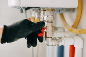 gloved hand adjusts a valve on industrial equipment, showcasing industrial maintenance work. the image highlights the precision and care involved in technical operations. gas boiler taps.