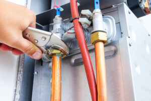 plumber repairing a gas boiler of a heating home system in the boiler room. close up, selective focus.