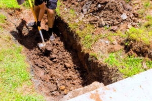 worker digging trench with shovel for a drainage pipe